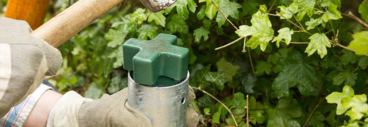 Person hämmert Pfosten in Bodenhülse